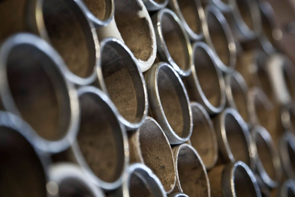 Närbild av tomma cylindriska metallrör ordnade i täta rader.